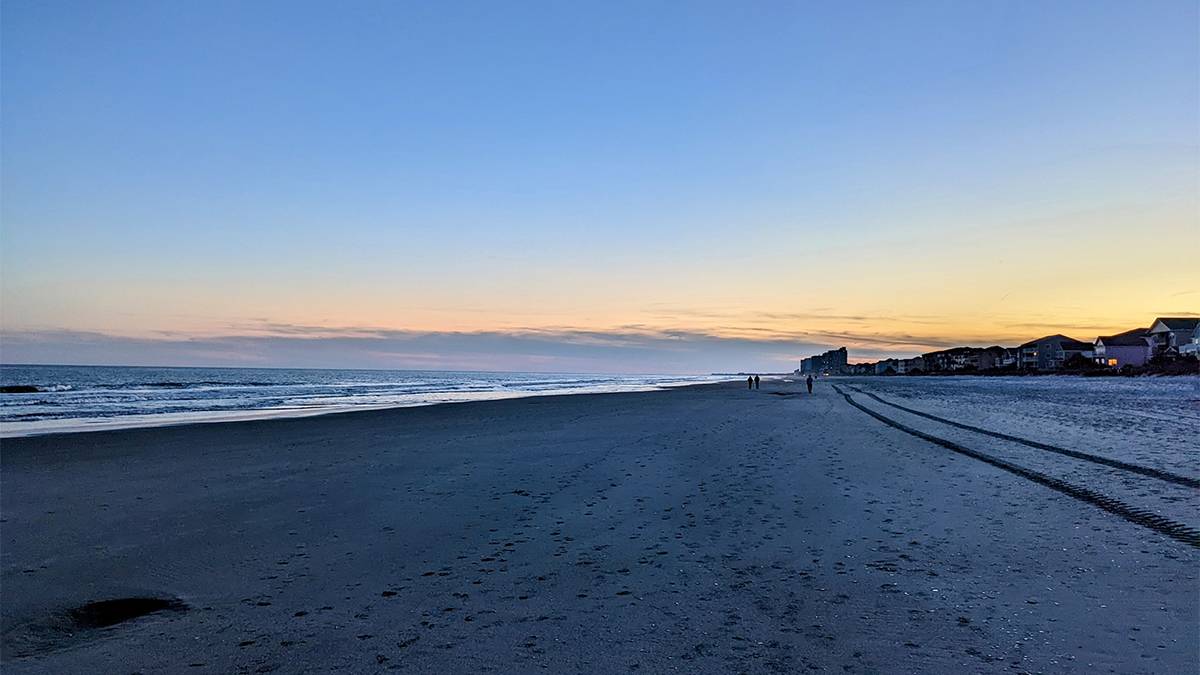 Wide shot of Surfside Beach at sunset with people in the distance in Myrtle Beach, South Carolina, USA