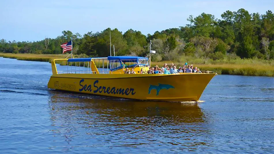 crowd of people waving to camera from the Sea Screamer Dolphin Cruise while in the water in Myrtle Beach, South Carolina, USA