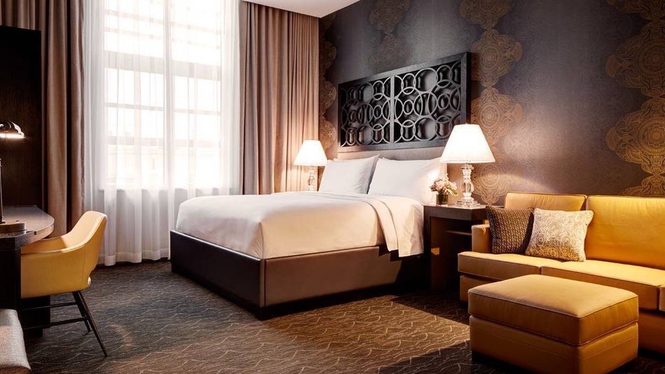 Dimmly lit hotel room with chocolate brown wallpaper and gold furntirure