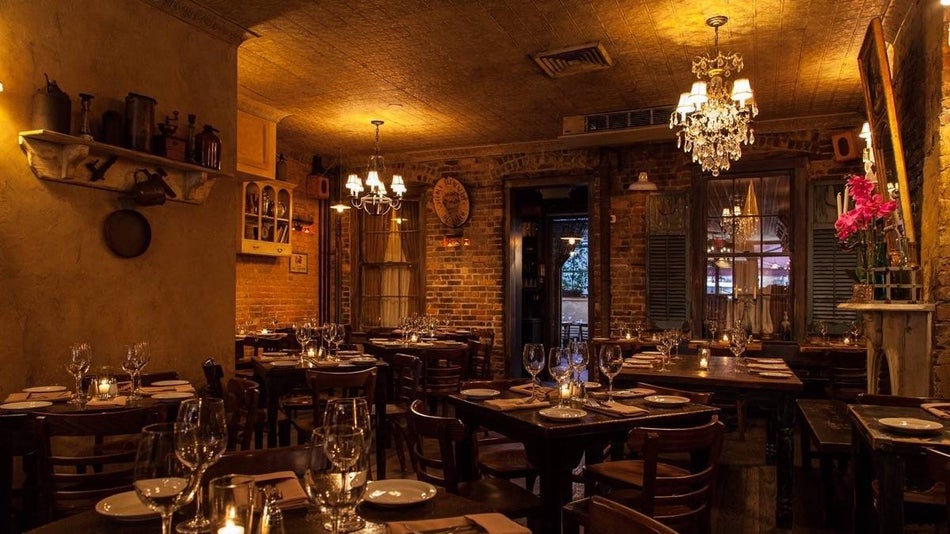 Dimmly lit dining room with chandeliers and tables set with wine glasses at UVA in New York City
