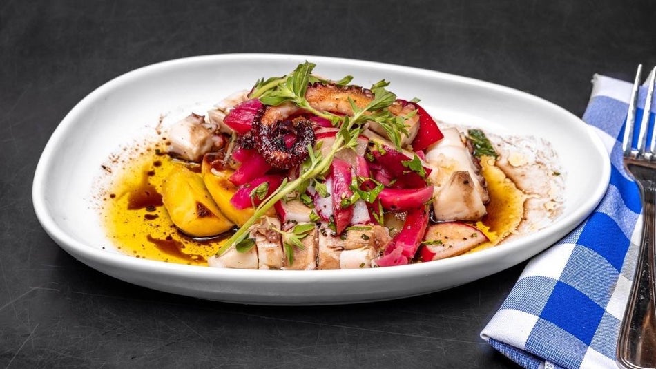Colorful food on a white plate with a blue checked napkin and fork beside it
