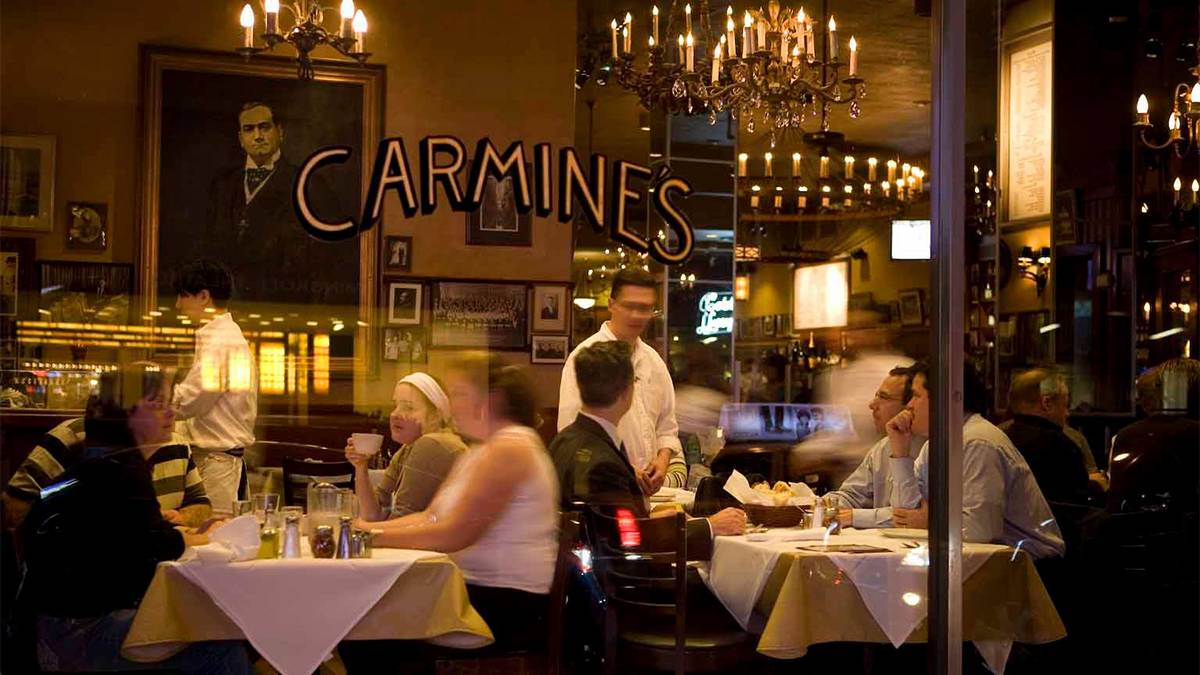 View looking in the window at Carmines with their logo on the window and people dinging inside in NYC, New York, USA