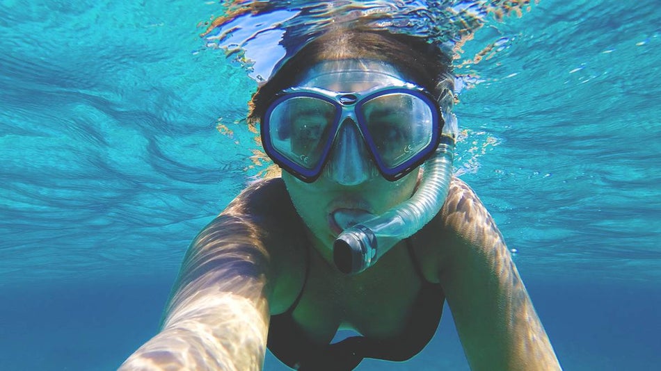 Close up of a girl snorkeling in bright blue water