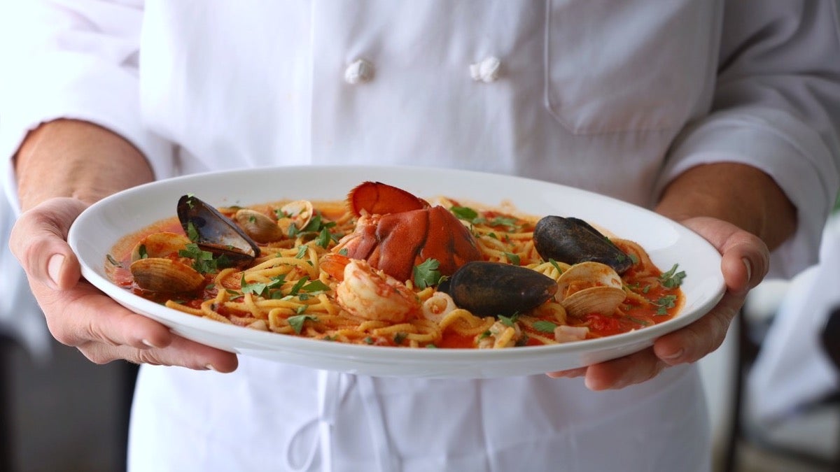 chef holding a plate of lobster pasta
