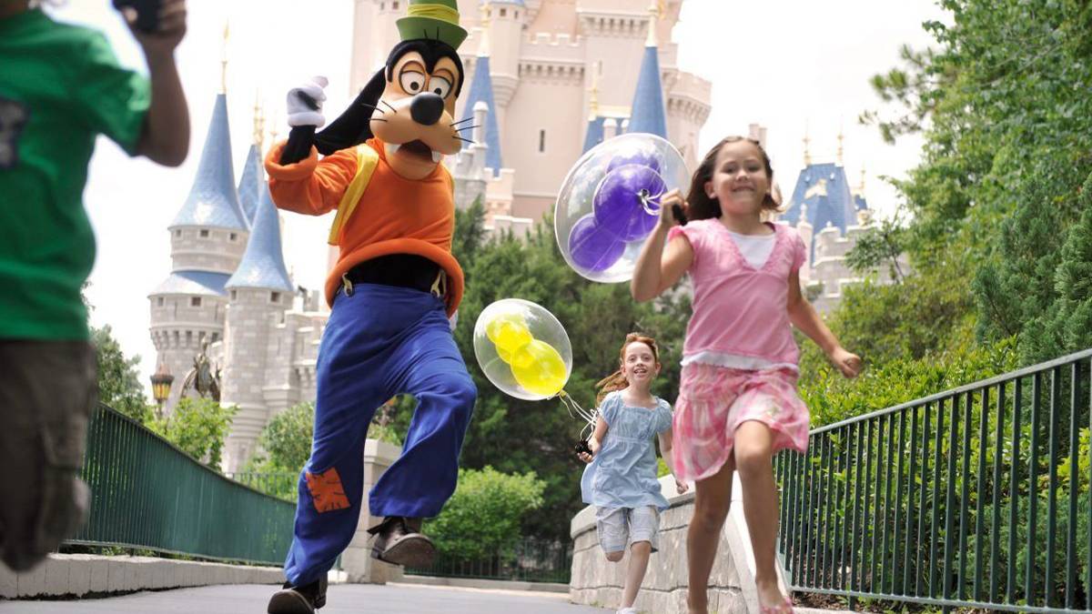 Goofy and Kids Skipping down a sidewalk with Cinderella's castle behind them at Walt Disney World's Magic Kingdom - Orlando, Florida, USA