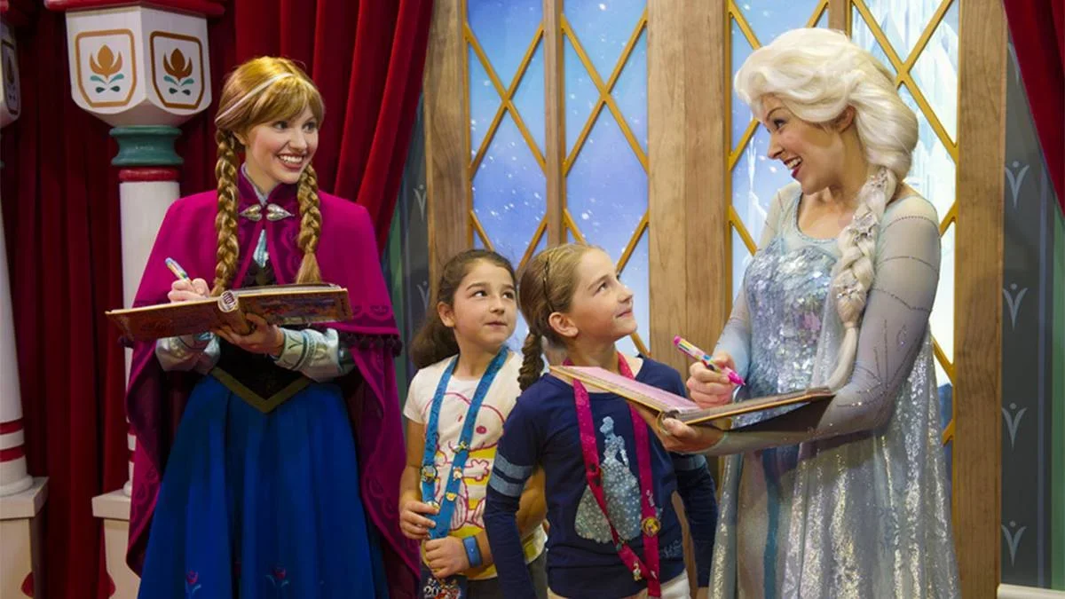 Elsa and Anna with two young girls signing their autograph books at Walt Disney World in Orlando, Florida, USA
