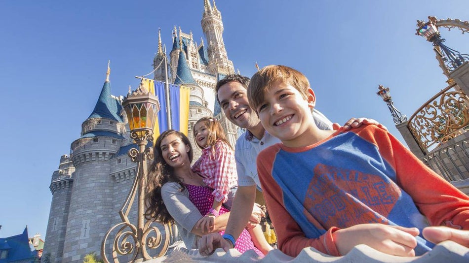 family with two children standing in front of disney castle at walt disney world daytime