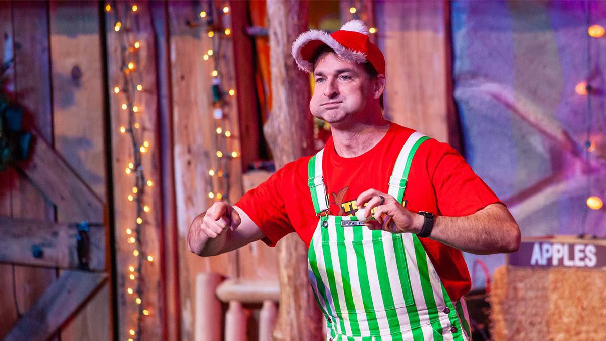 Man with a red shirt and green and white striped overalls with ping pong balls in his mouth at The Comedy Barn in Pigeon Forge, Tennessee, USA