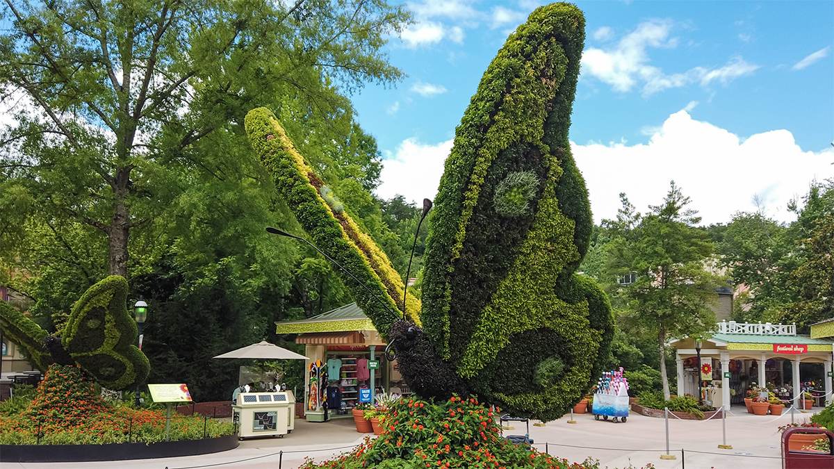 Close up of a butterfly sculpture with another one in the background along with trees and a souvenir stand at the Flowers and Food Festival at Dollywood in Pigeon Forge, Tennessee, USA