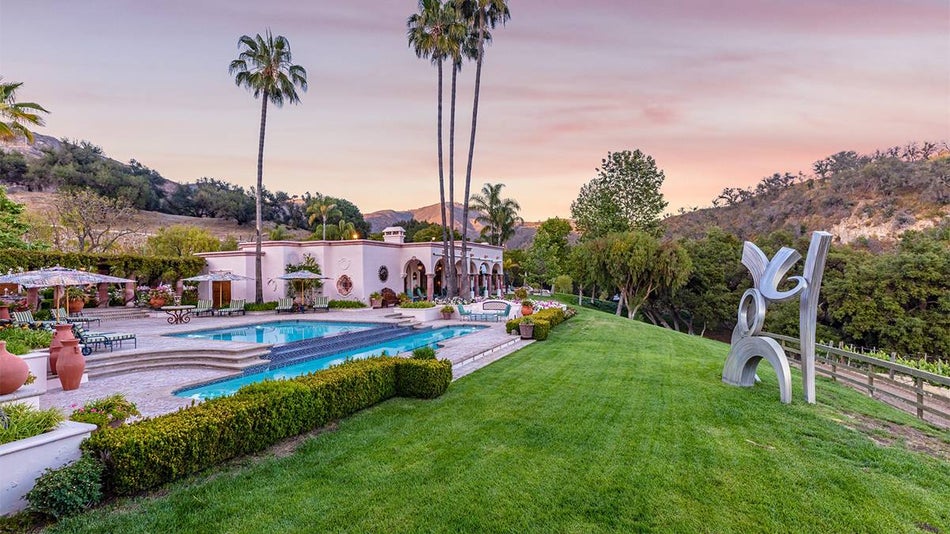 Wide shot of Rosenthal - The Malibu Estate with a pink sunset behind it and lots of lush greenery surrounding it in San Diego, California, USA