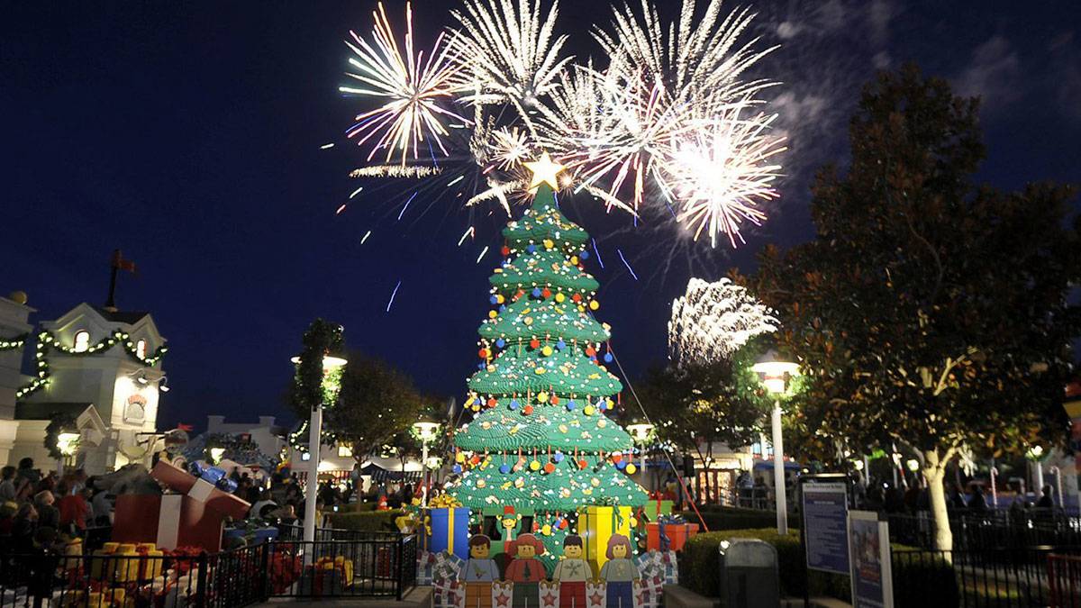 fireworks over LEGOLAND amusement theme park with christmas tree and presents in foreground during Holiday Snow Days in San Diego, California, USA