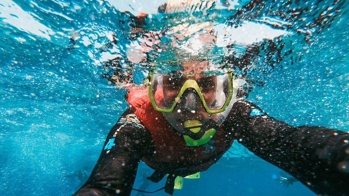 underwater photo of man snorkeling in blue ocean water