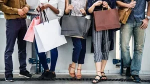 close up of women holding shopping bags standing against a wall