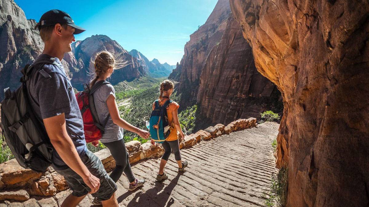 family of three hiking through mountains and trails in Zion National Park near Las Vegas, Nevada, USA