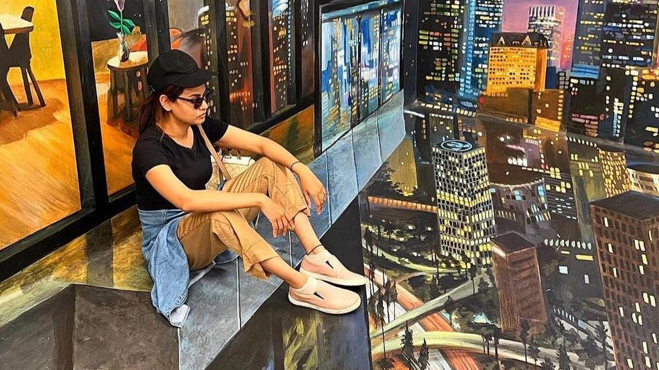 woman sitting on a building ledge overlooking city buildings at the Museum of Illusions in LA