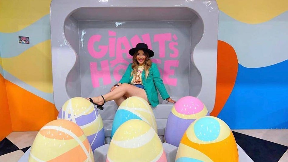 Woman sitting on giant eggs in an egg carton at the Museum of Illusions in Los Angeles