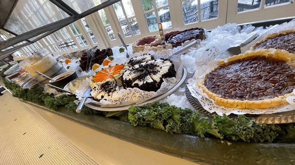 Pies and cakes on a buffet bar surrounded by ice and greenery