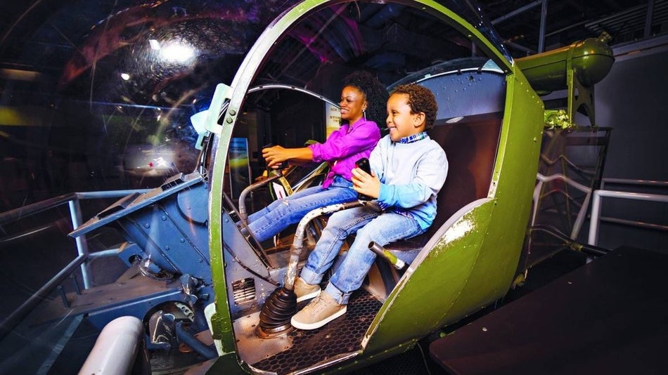 Mother and son in a green capsule simulator ride at Intrepid Sea, Air & Space Museum