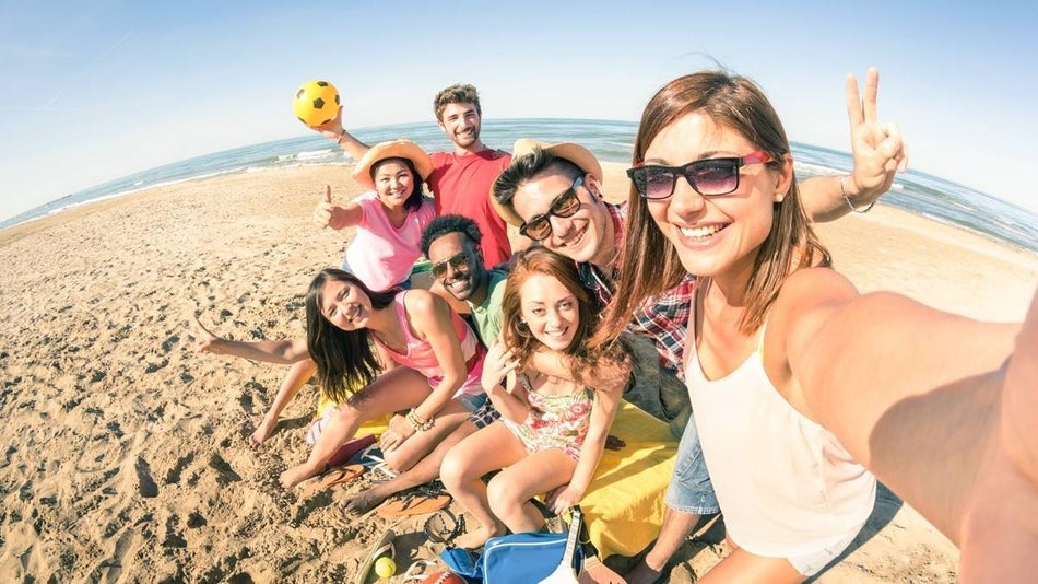 Group of friends huddled together for a selfie on the beach