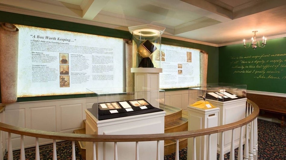 interior museum exhibit with green walls and artifacts from the Boston Tea Party