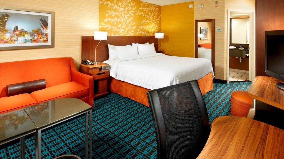 hotel room with yellow walls, green carpet, orange furniture.