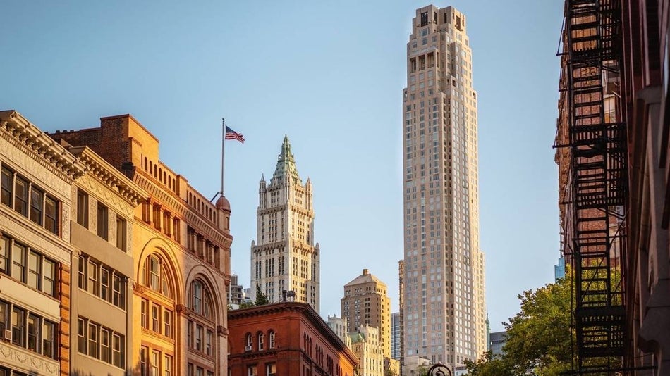 Exterior view of Four Seasons Hotel New York Downtown against a blue sky with victorian buildings in the foreground and background