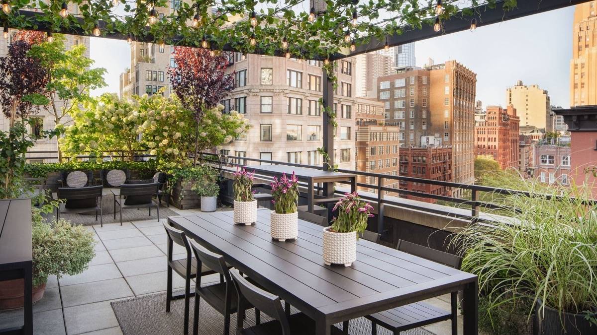 Pergola covered outdoor patio with greenery and hanging lights overlooking the city streets of New York City