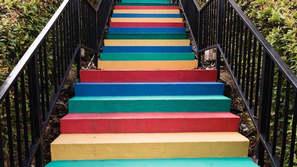 Multicolored concrete stairs with black metal railing surrounded by greenery