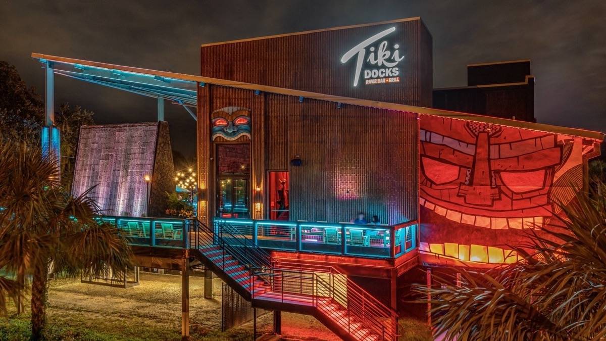 Exterior view of Tiki Docks building with colorful lights, palm trees, and tiki decorations