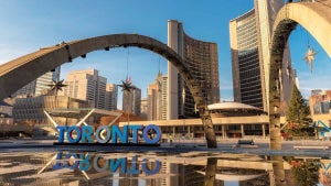 Blue "Toronto" sign with skyscraper in the background under a blue sky