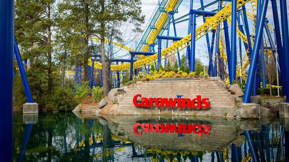 Red carowinds sign next to a body of water with a roller coaster in the background