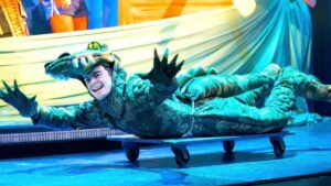 Actor in a crocodile suit on a dolly on stage