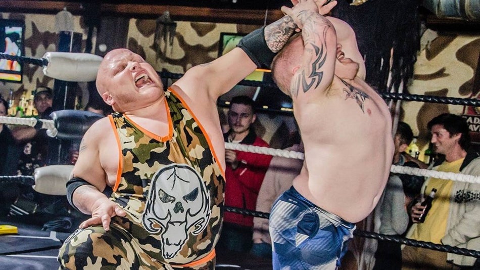 Two micro wrestlers in a ring wrestling surrounded by a crowd
