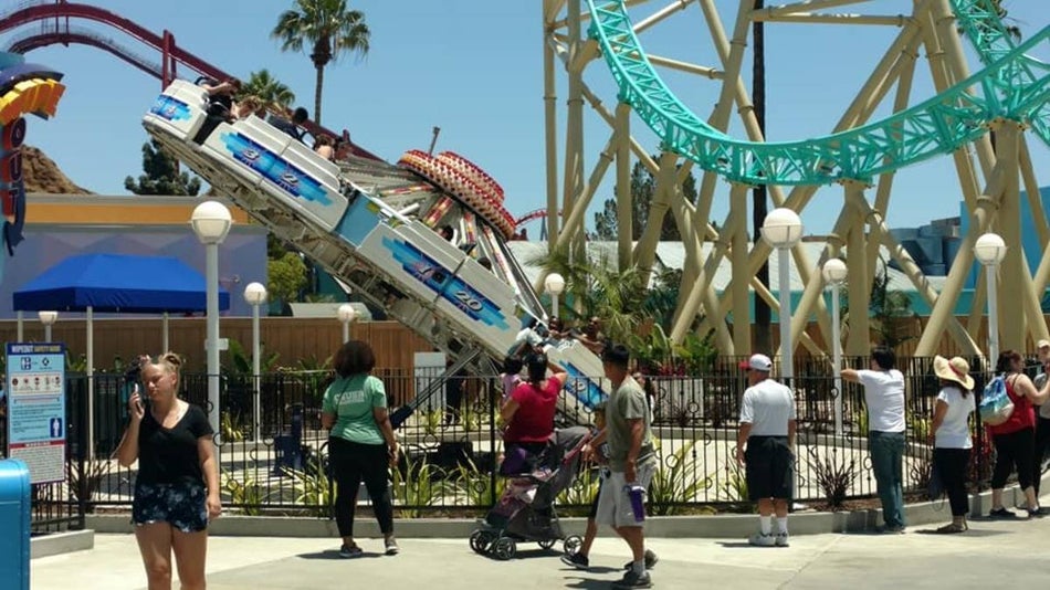 Theme park setting with a white disk like spinning ride and a roller coaster in the background
