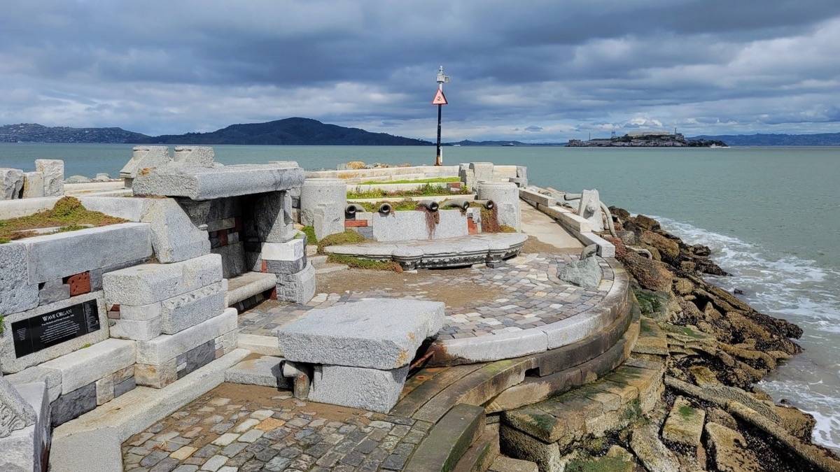 concrete structure built at the end of a pier with ocean and Alcatraz island in the background