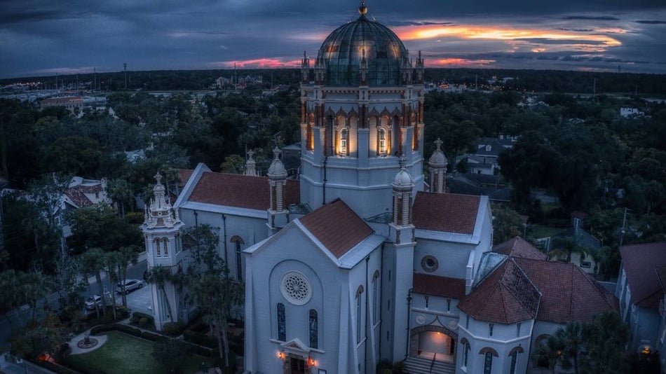 Aerial shot of spanish style cathedral at dusk with sunset in the background