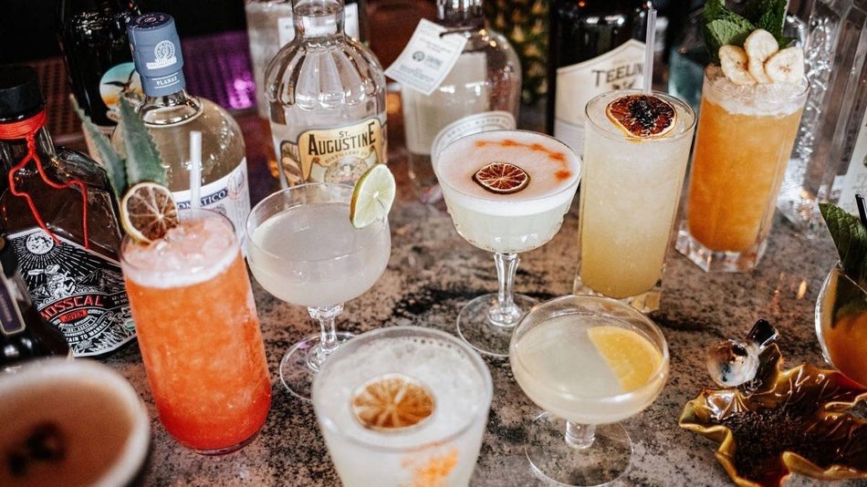 Various cocktails in glasses with alcohol bottles on a granite countertop