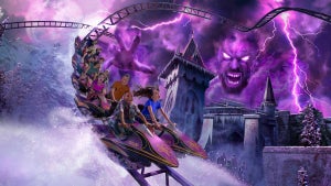 Rollercoaster with a purple lightnight lit sky with a monster in the clouds and a castle in the background at Busch Gardens Williamsburg