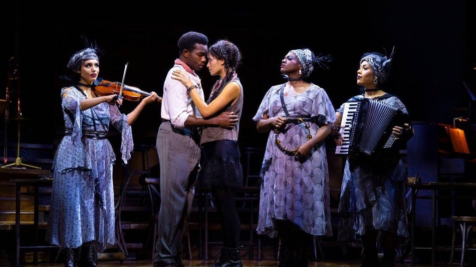 Cast members of Hadestown on stage with musical instruments