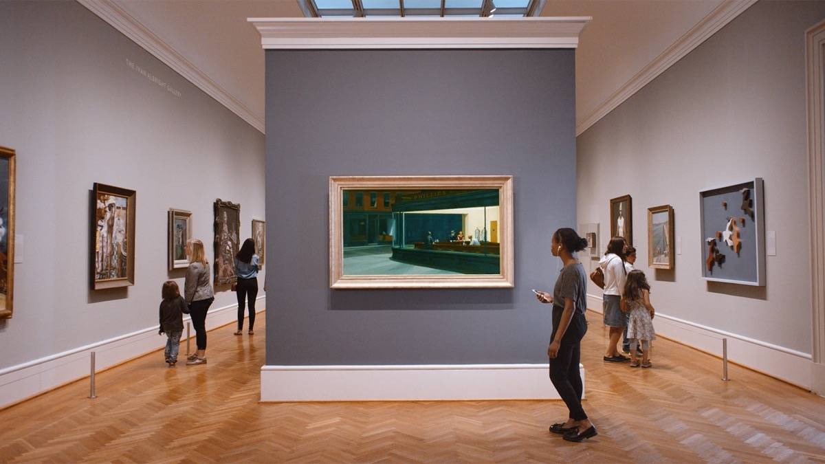 Woman looking at a piece of art while others look at more art along other walls