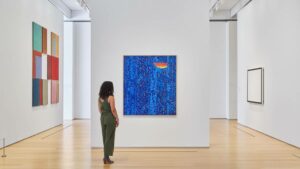 Lone person stands looking at a blue piece of art on the wall