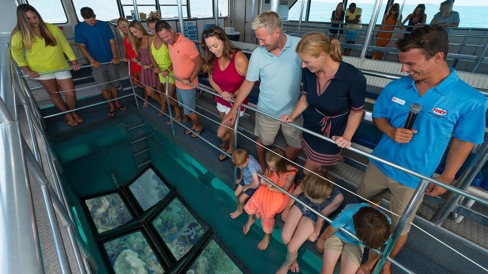 People inside of a glass bottom boat key west looking down at the glass bottom at coral reef