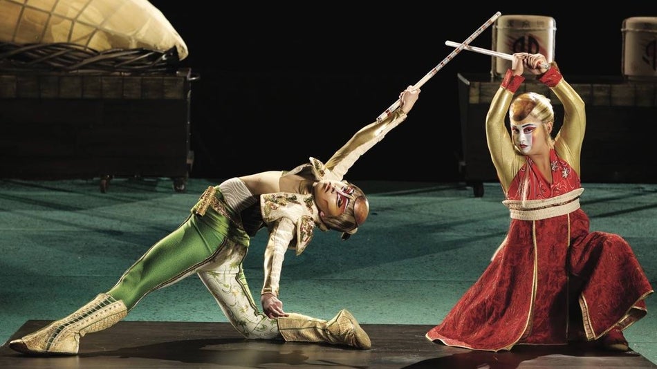 Two women in acrobatic stance on stage for Ka by cirque