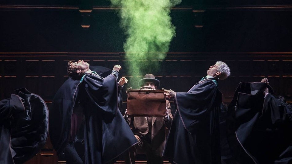 Two wizards leaning back from a suitcase billowing green smoke