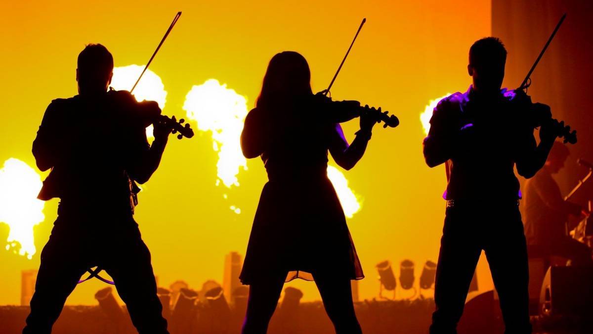 Silhouette of three musicians playing instruments with a yellow background and flames behind them