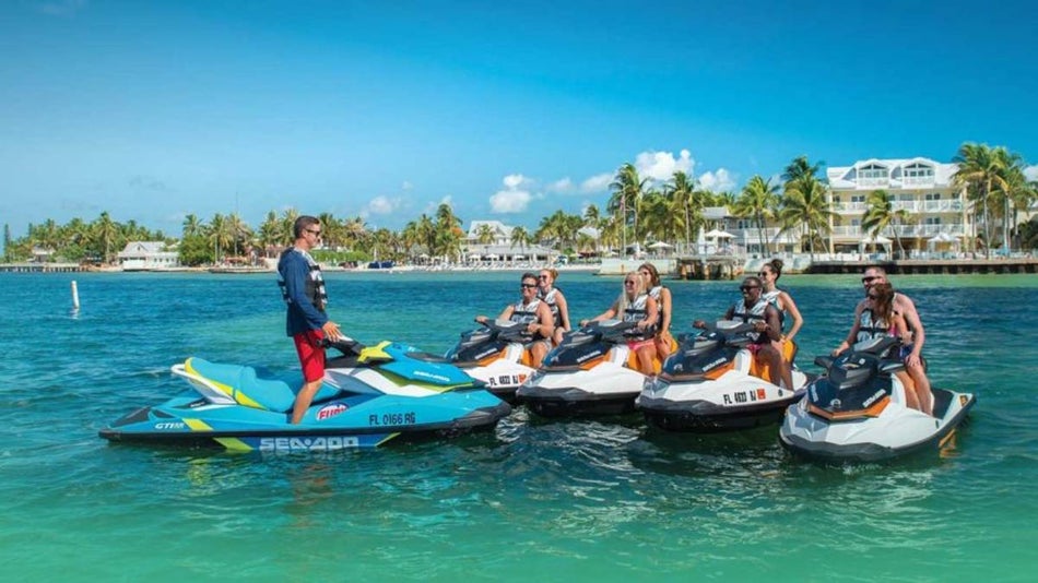 Tour leader on a jet ski in front of 4 other jet skis with people on them in the ocean