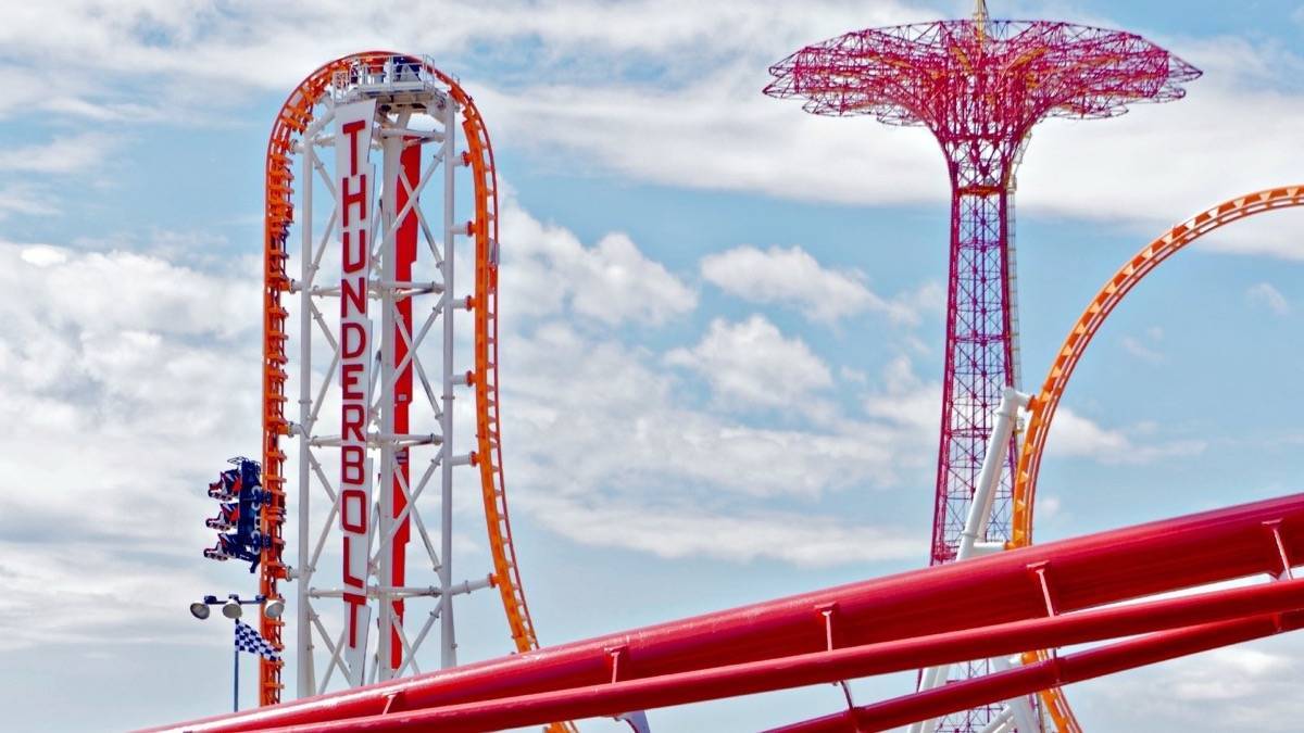 people riding a red and orange roller coaster