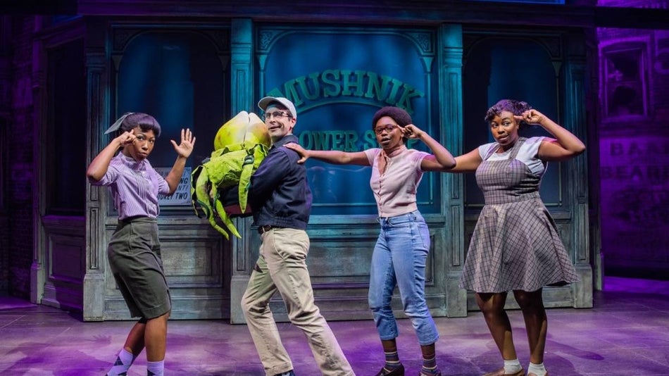 Four cast members on stage performing for little shop of horrors broadway