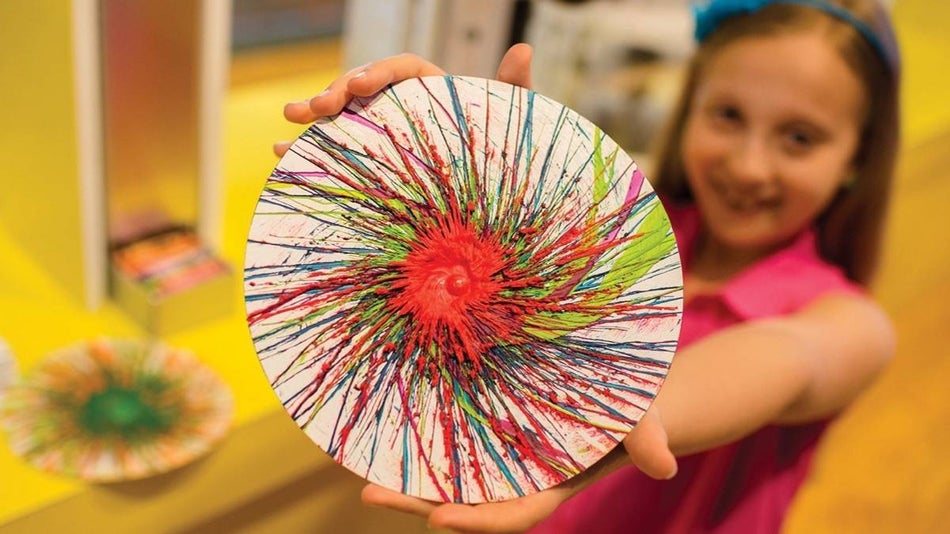 child holding a crayola melted crayon spin art