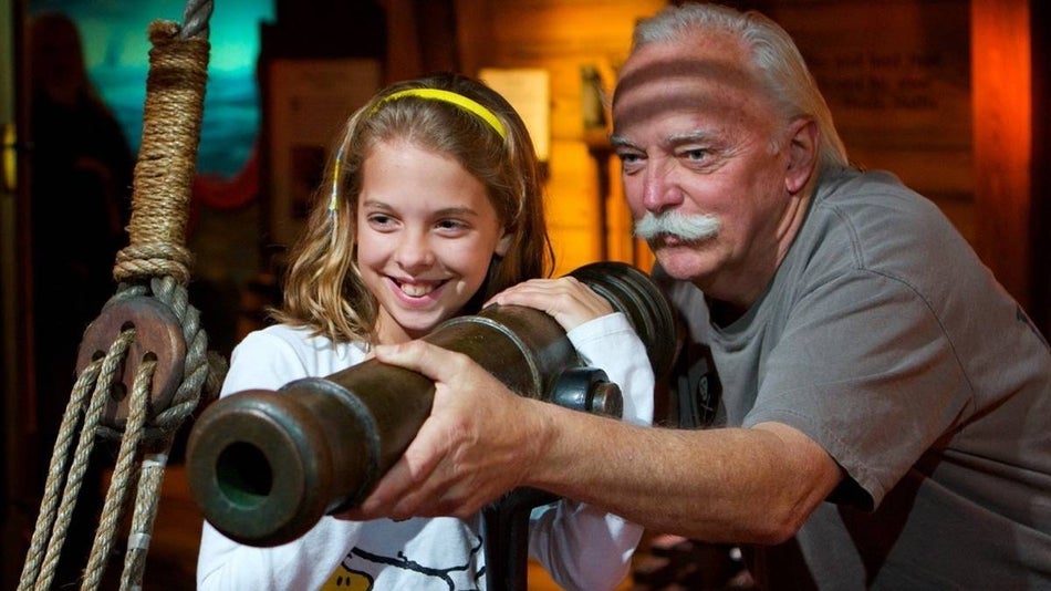 Older man holding a canon next to a younger girl at the st augustine pirate & treasure museum